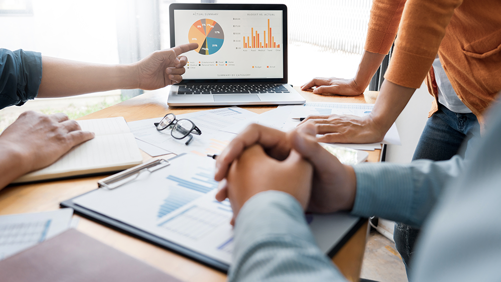 business owner reviewing performance charts with a digital marketing consultant on a laptop