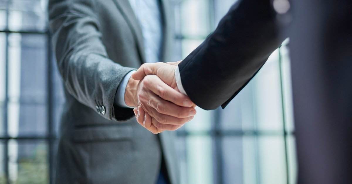 Two diverse professional business men executive leaders shaking hands at office meeting